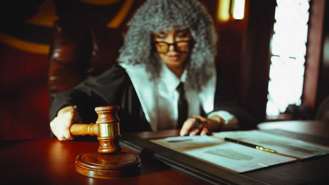 Judge striking the gavel while reviewing legal documents at a courtroom desk. Judge striking the gavel while reviewing legal documents at a courtroom desk.