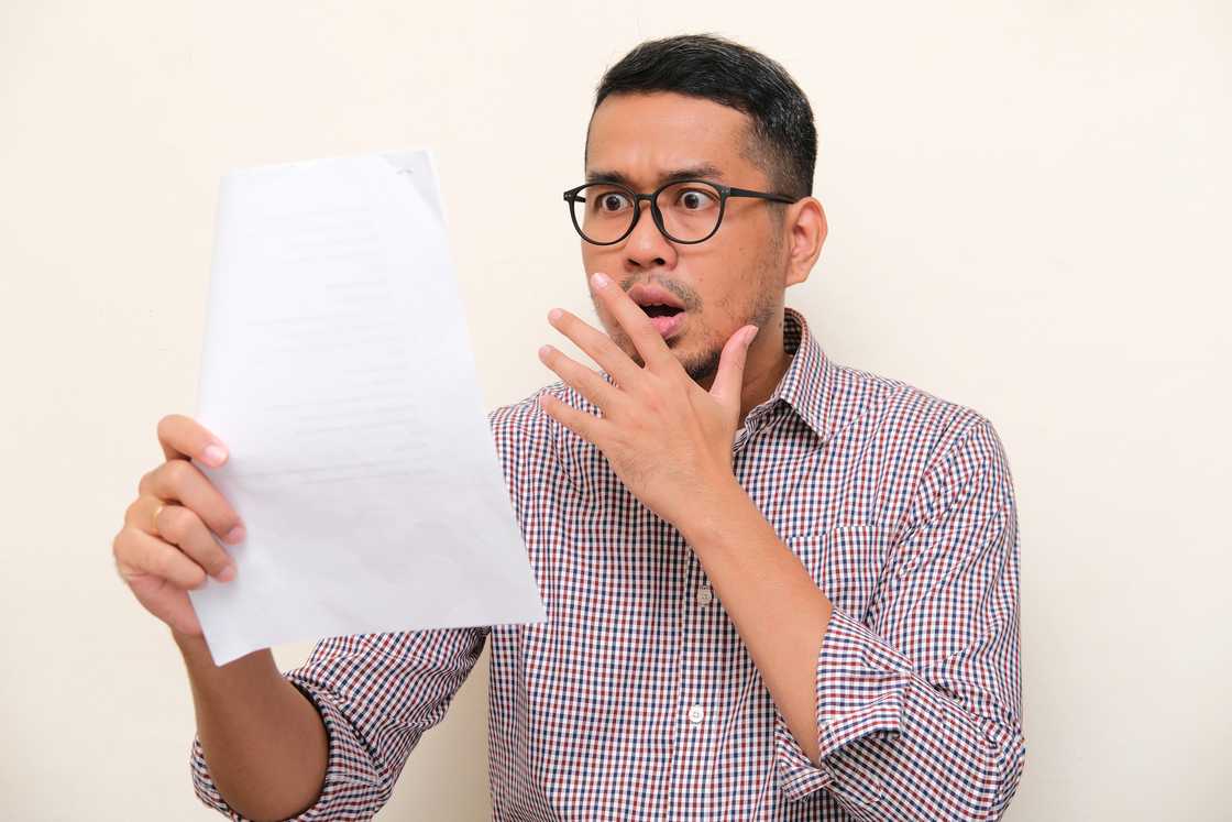 A man shocked while reading a document A man shocked while reading a document