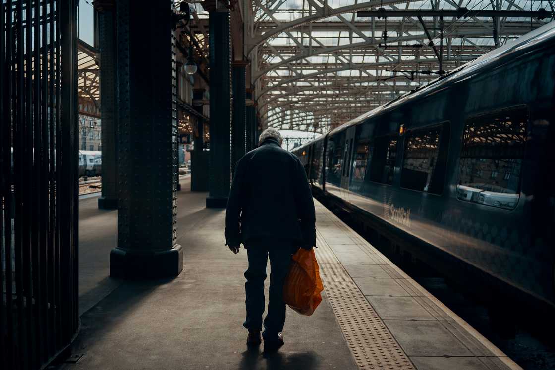An older person walks into a train station. An older person walks into a train station.