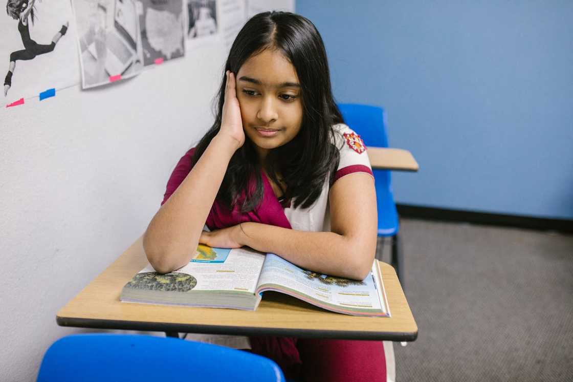 A student in a maroon outfit studies a textbook.