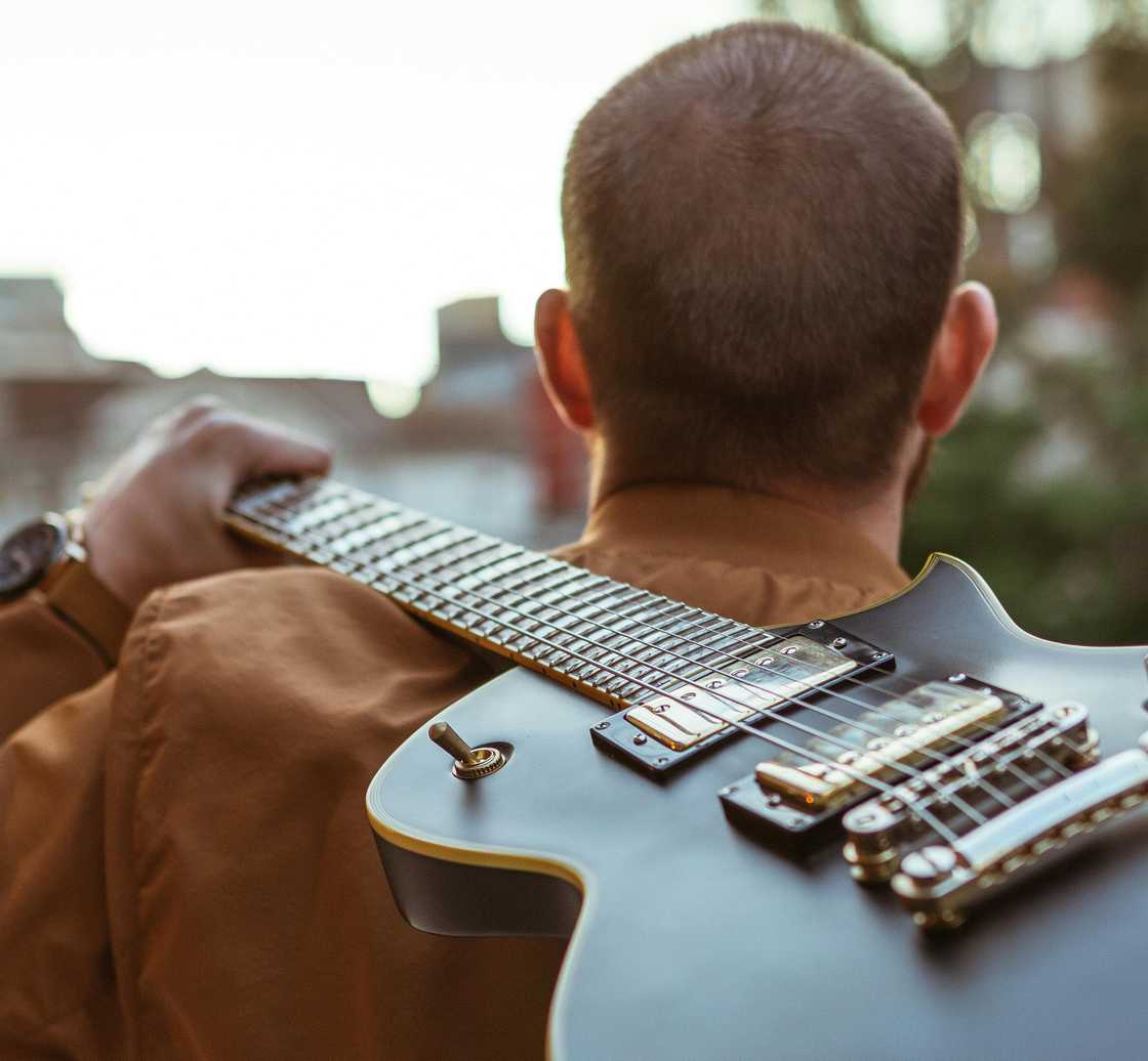A man carrying a guitar on his back