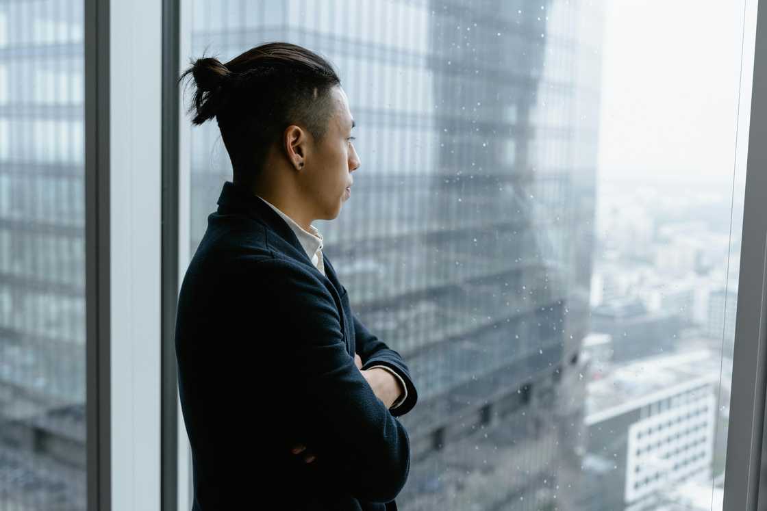 A thoughtful young man looking through window