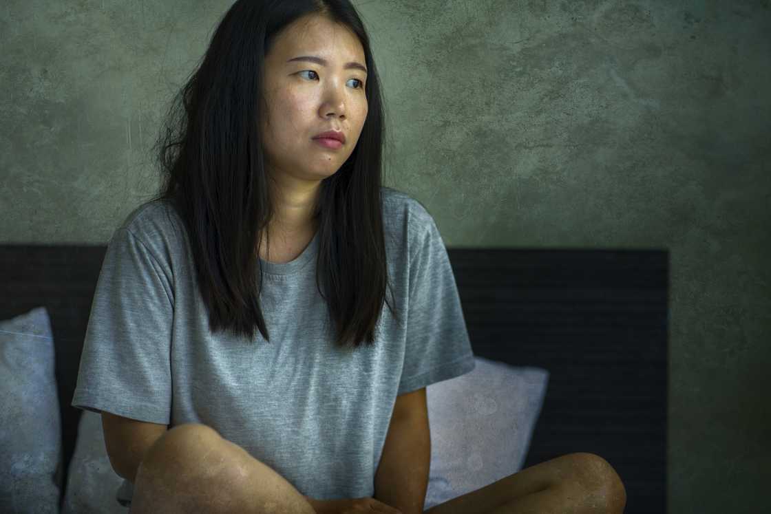 A worried mid adult woman sitting on bed A worried mid adult woman sitting on bed