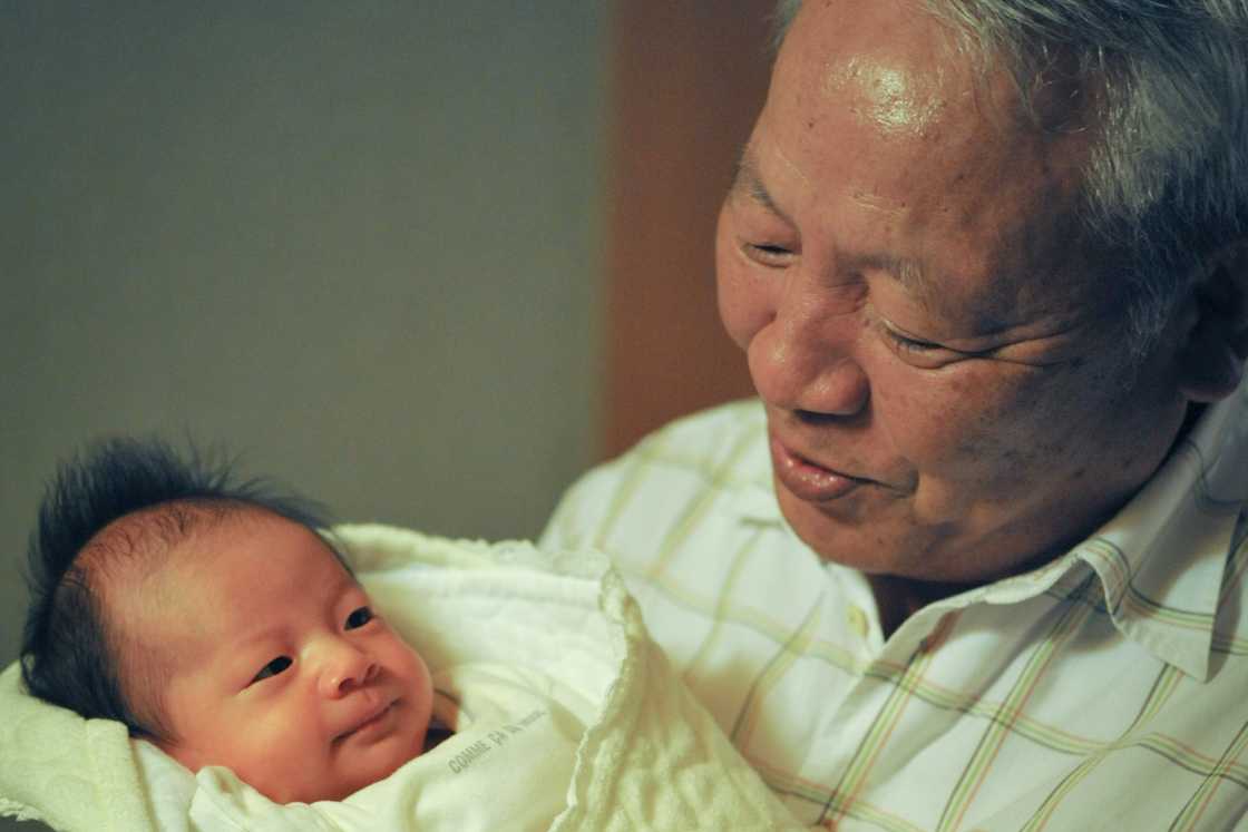 An older man is looking at a baby An older man is looking at a baby