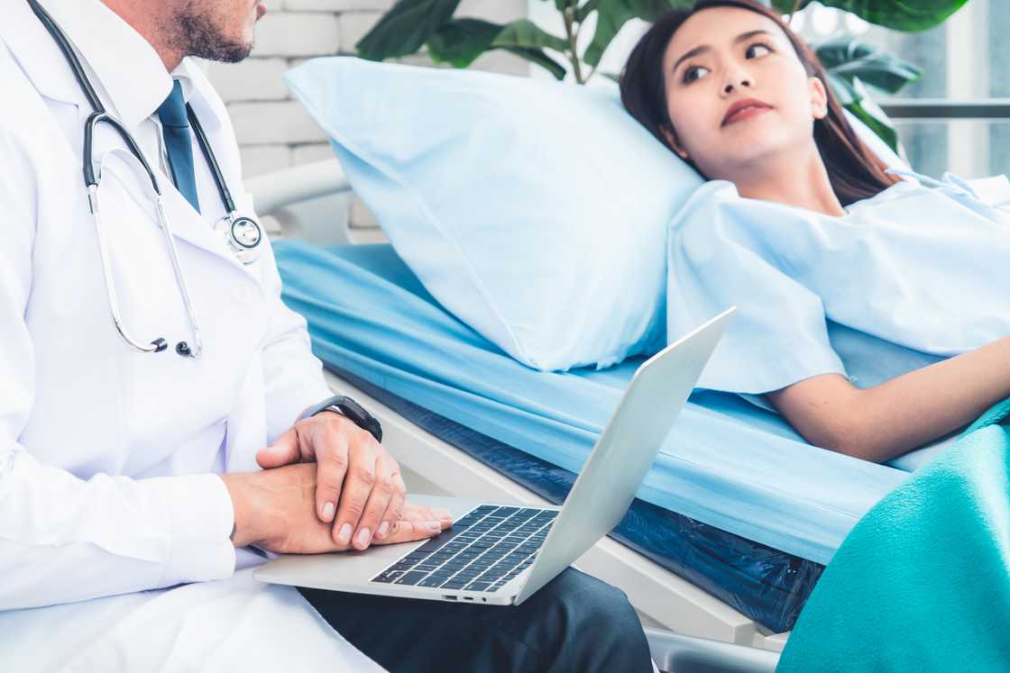 A doctor talking to a patient lying in hospital bed