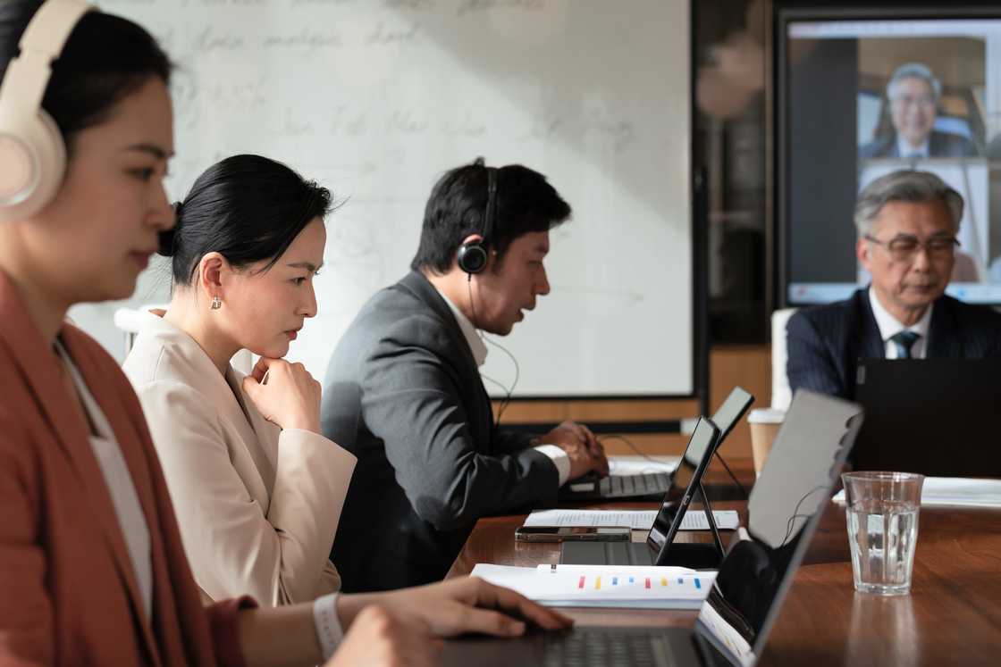 Managers listen to a call playback in a BPO office meeting.