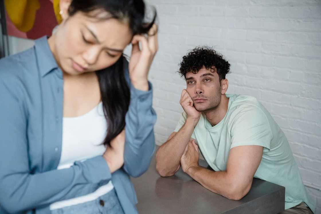 A couple standing apart in a living room during a tense conversation.