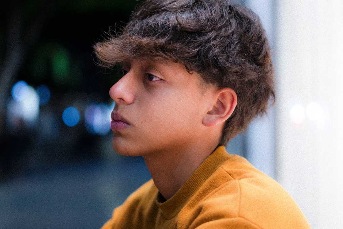 A young person looks off to the side with a distant expression, appearing deep in thought.