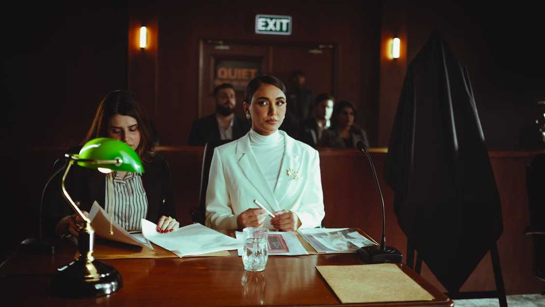 Woman sitting at a courtroom table reviewing documents during a hearing. Woman sitting at a courtroom table reviewing documents during a hearing.