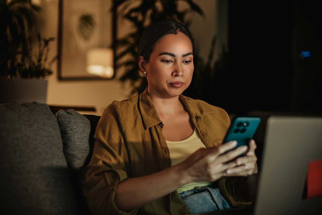 A serious lady is using her phone and laptop A serious lady is using her phone and laptop