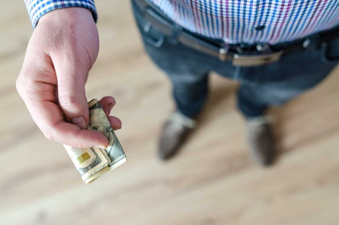 A person hands another folded paper money. A person hands another folded paper money.