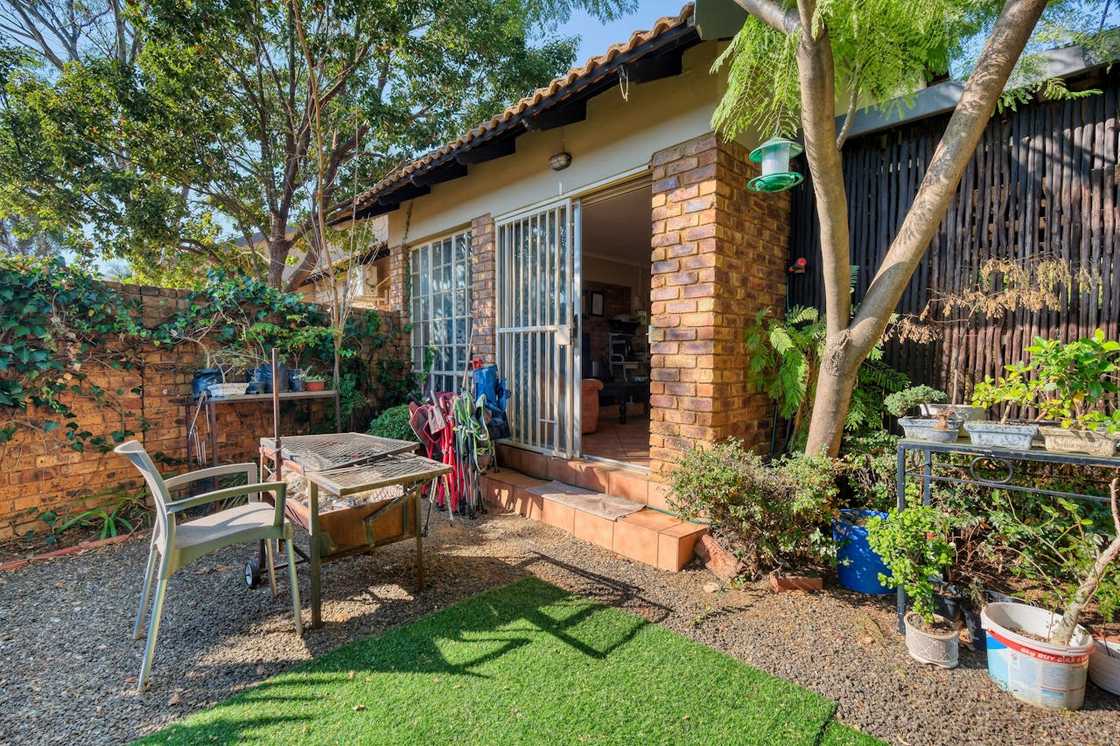 A small house sits in a quiet yard with garden tools outside. A small house sits in a quiet yard with garden tools outside.