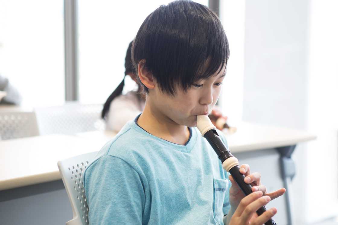 A young boy playing a flute