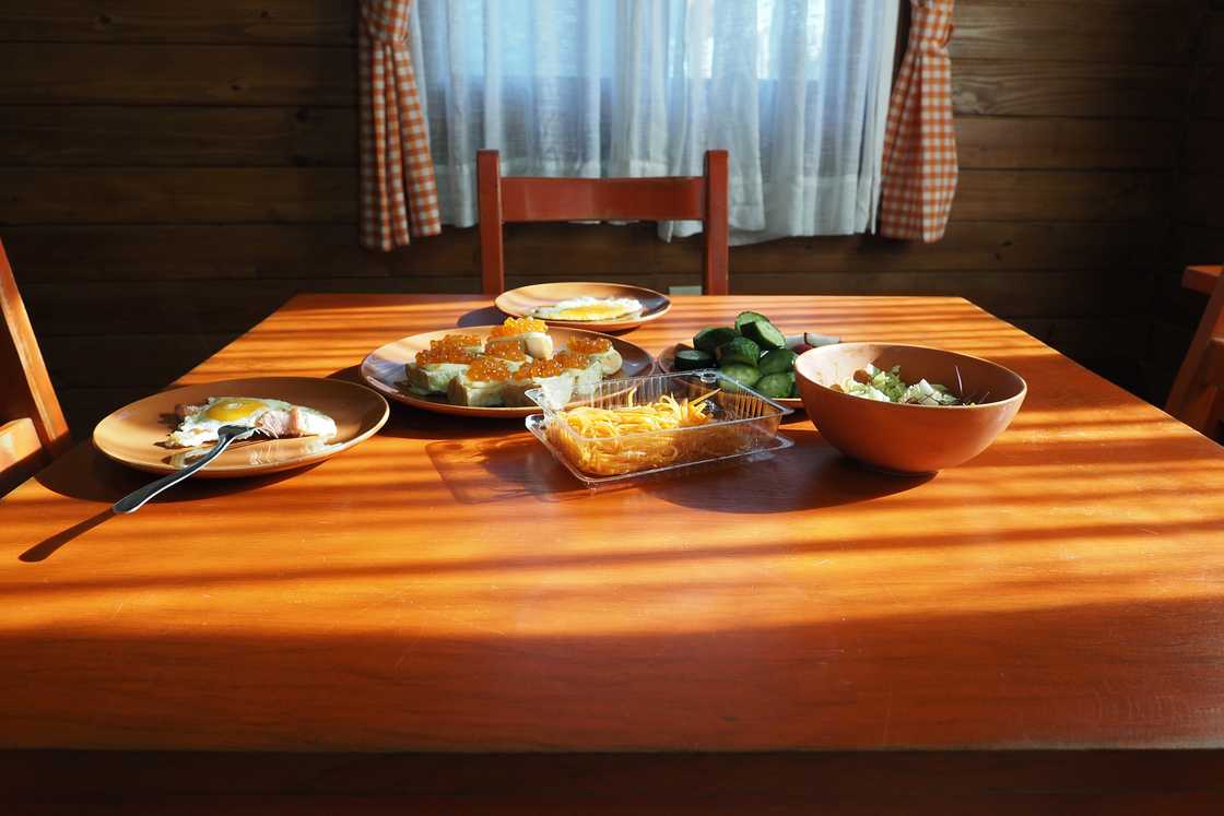 Wooden dining table in a sunlit room set with various dishes.