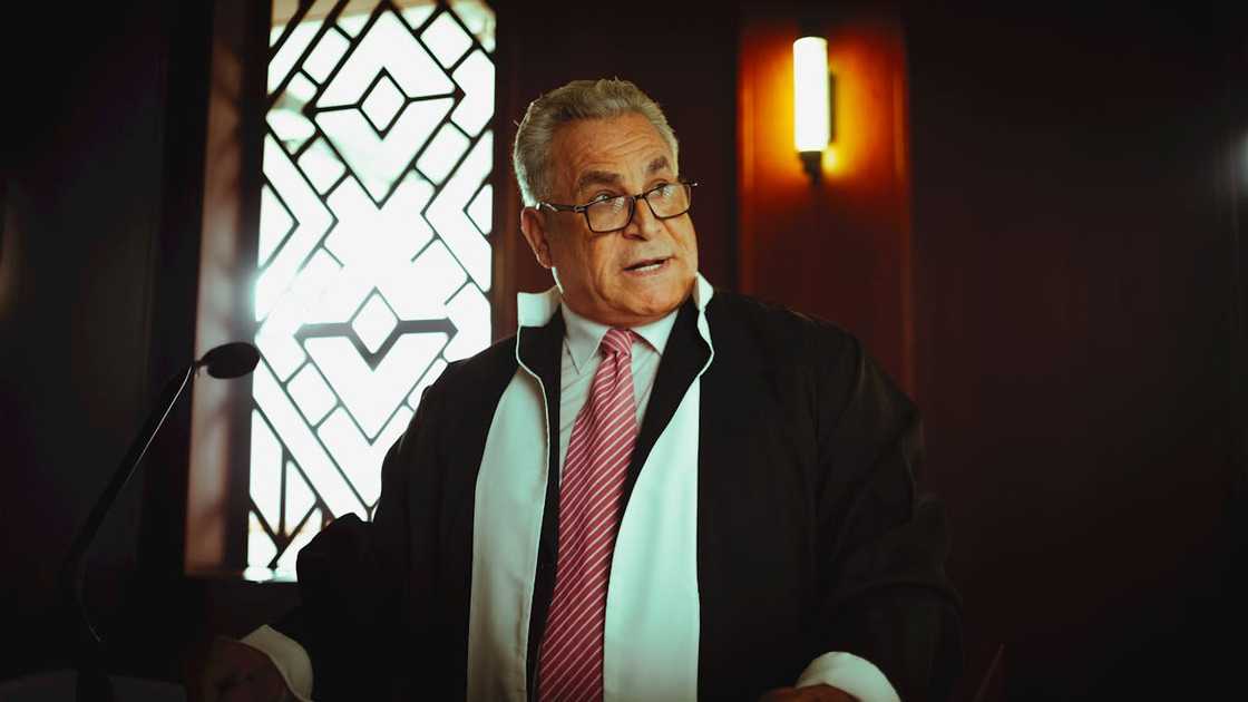 Judge speaking in a courtroom wearing judicial robes.