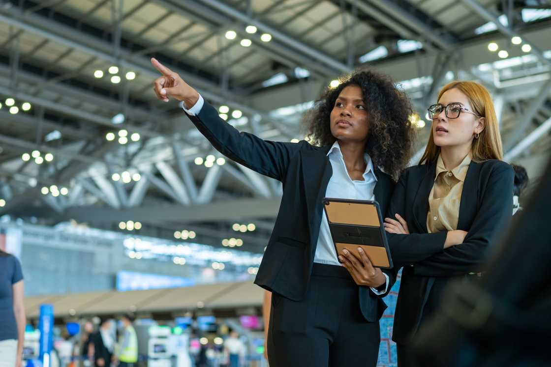 Airport terminal; woman and agent standing side-by-side. Airport terminal; woman and agent standing side-by-side.