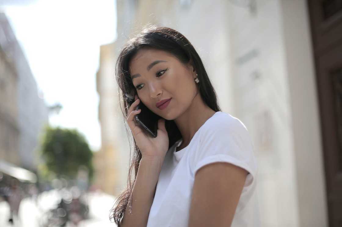 A woman speaks into a smartphone outside some buildings. A woman speaks into a smartphone outside some buildings.