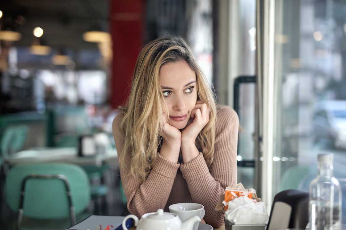 Pensive woman sitting alone in café by window. Pensive woman sitting alone in café by window.