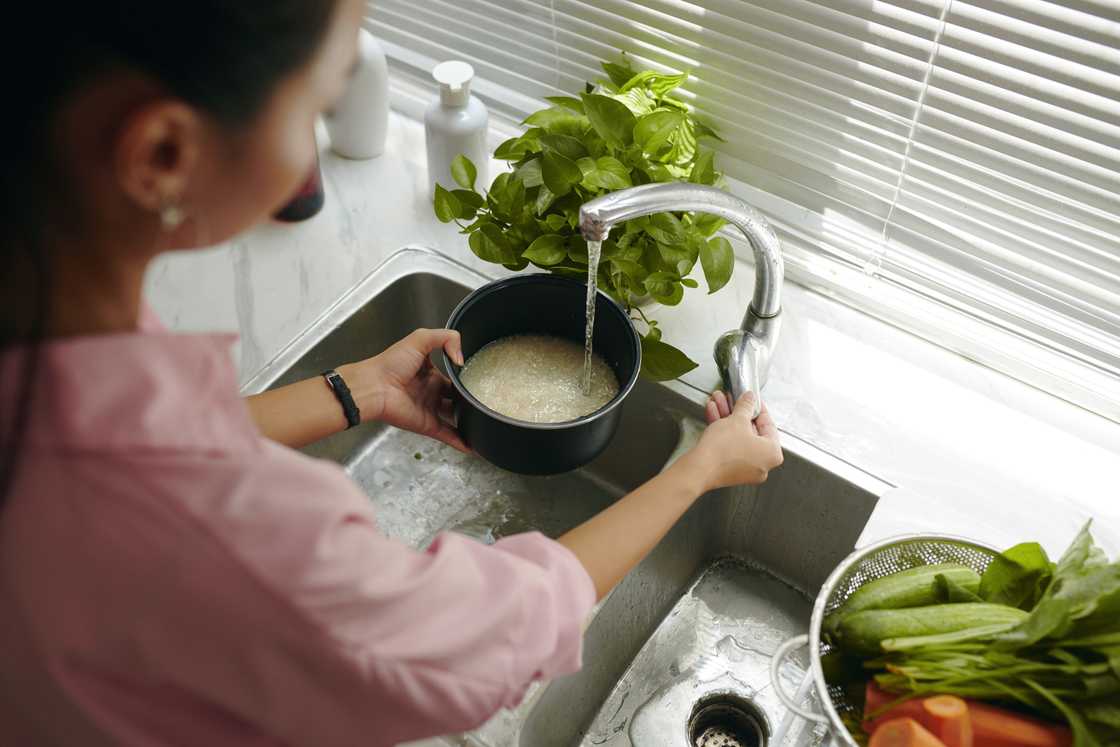 A lady in the kitchen is washing rice A lady in the kitchen is washing rice