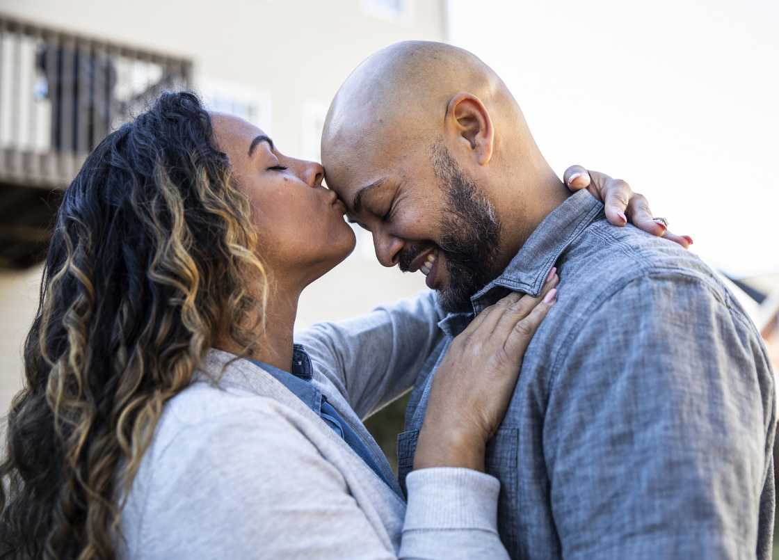 Wife and husband kissing outside their home.