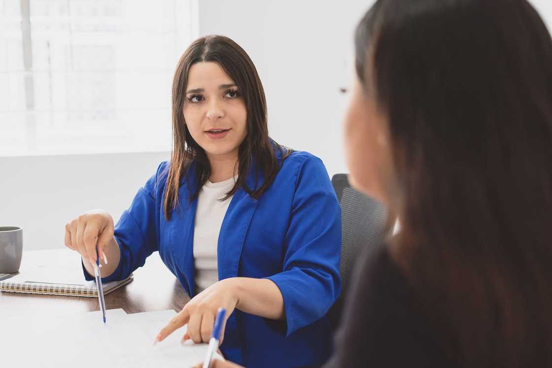 A woman in a blue blazer discusses documents during a meeting. A woman in a blue blazer discusses documents during a meeting.