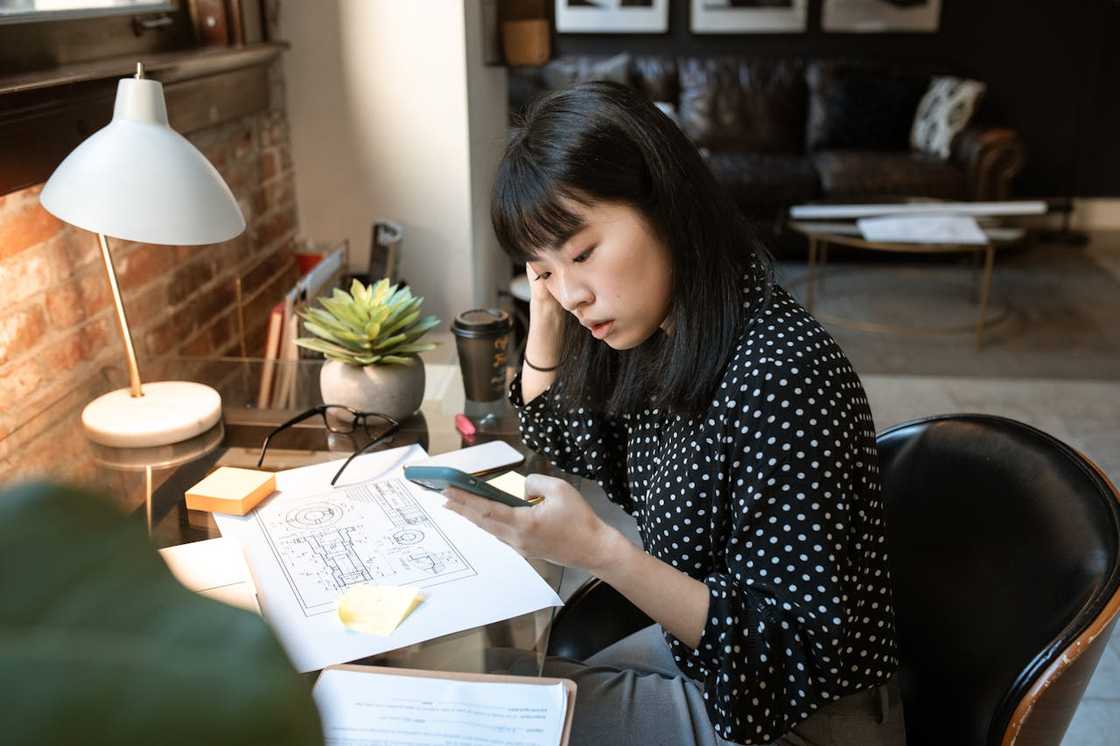 A woman speaks on the phone at her mansion at dusk.