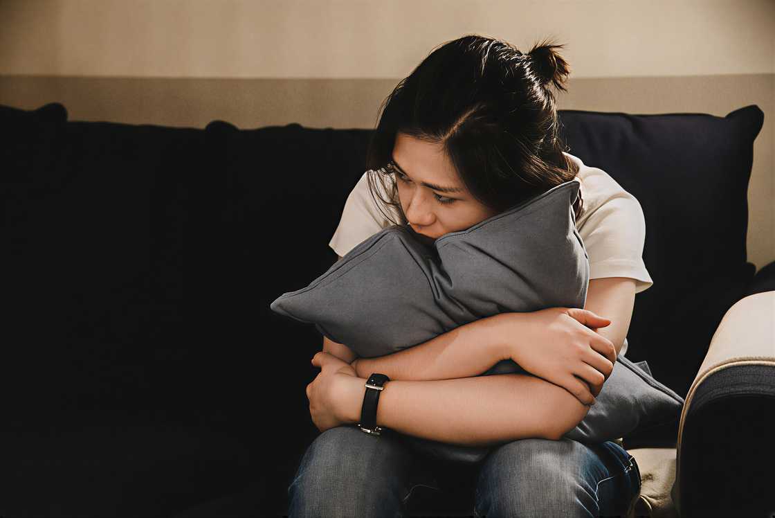 Depressed Asian woman sitting on a sofa Depressed Asian woman sitting on a sofa