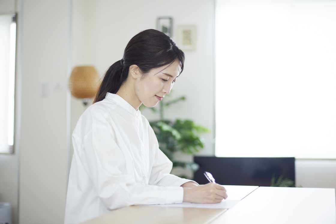 A woman signing documents at a desk in the living room