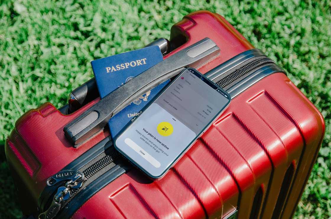 A passport and phone rest on a suitcase.