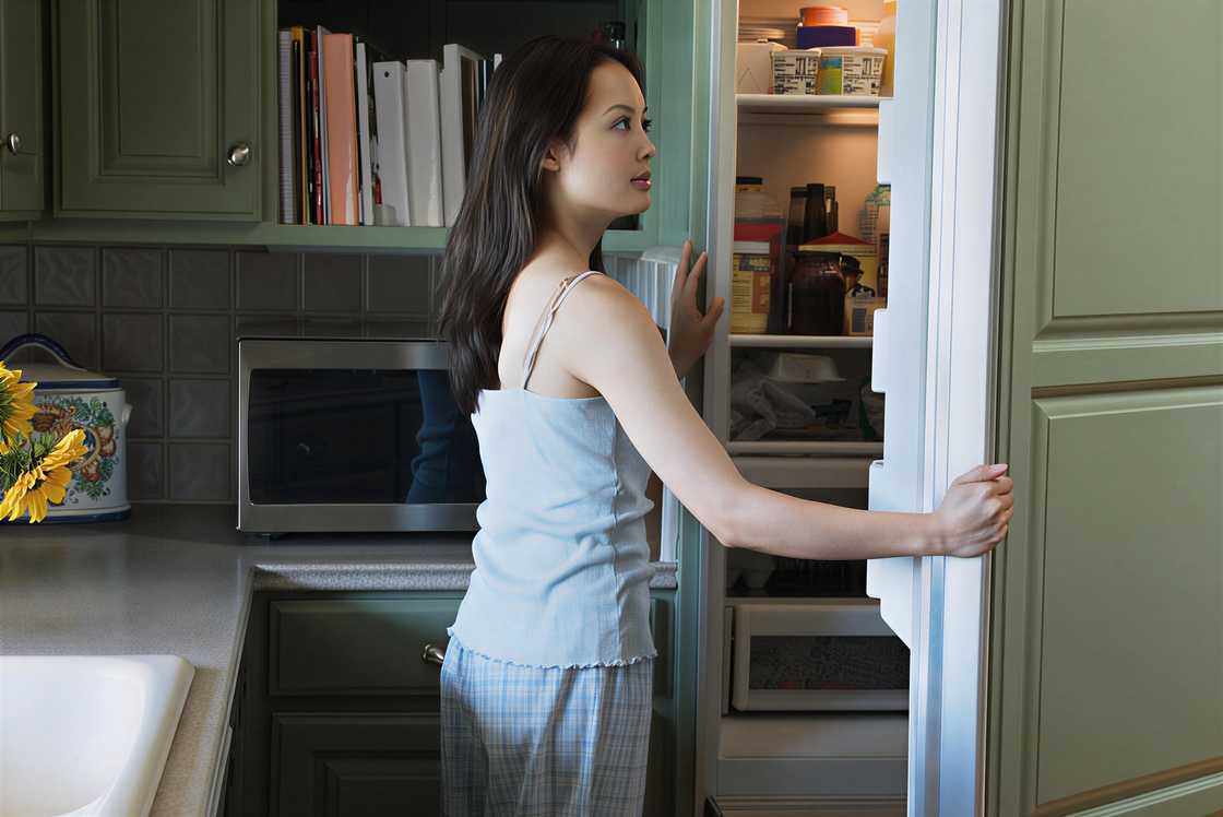 A woman is opening the refrigerator