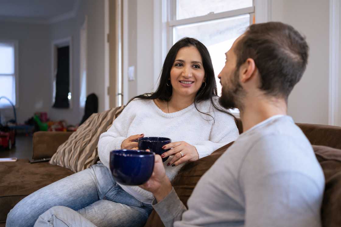 An adult brother and sister drinking tea in the living room