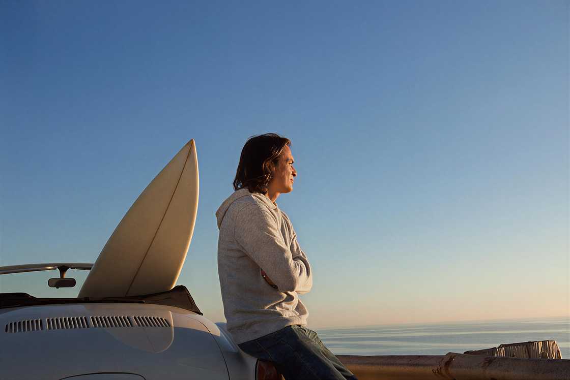 A man with a convertible car and a surfboard