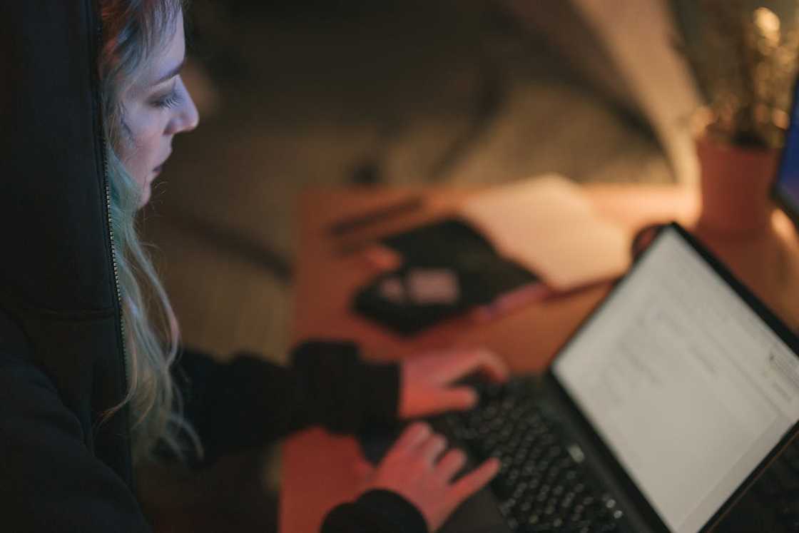 Woman in hoodie working on laptop at night. Woman in hoodie working on laptop at night.