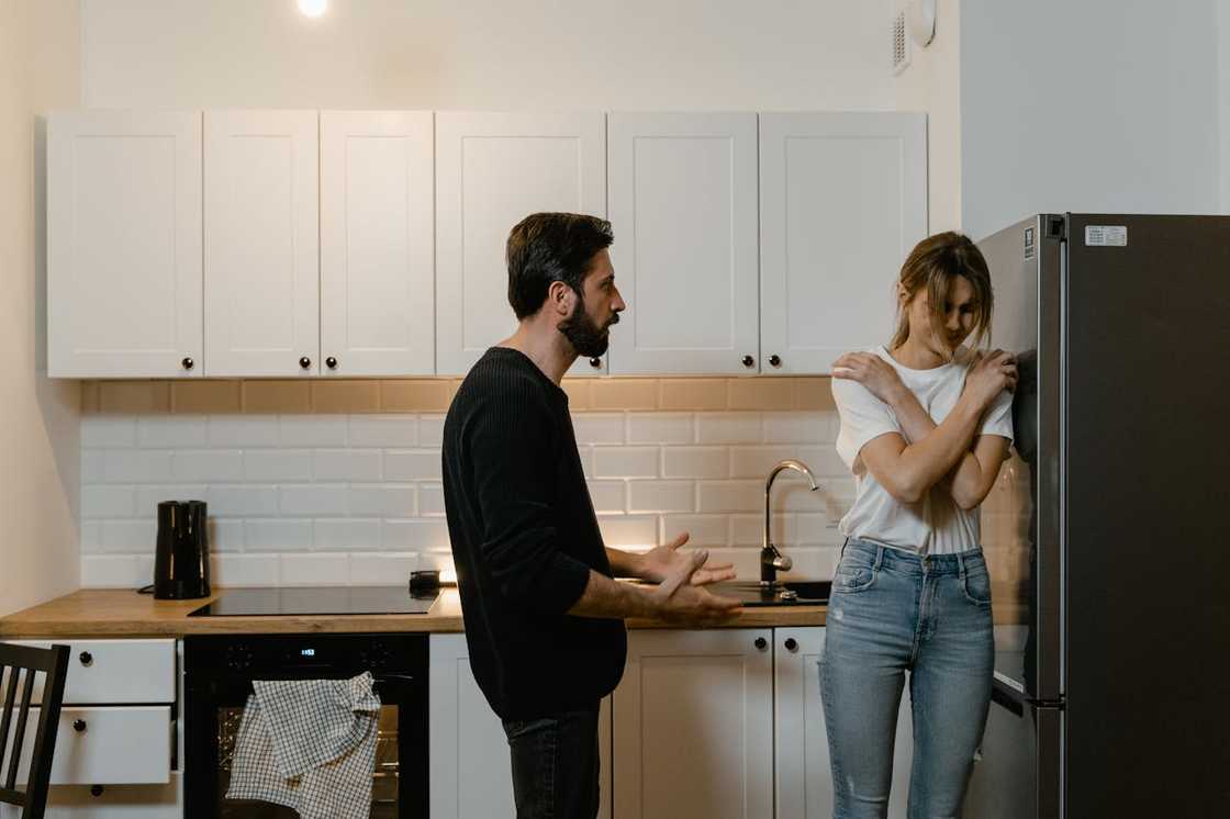 A man and a woman argue in a kitchen.