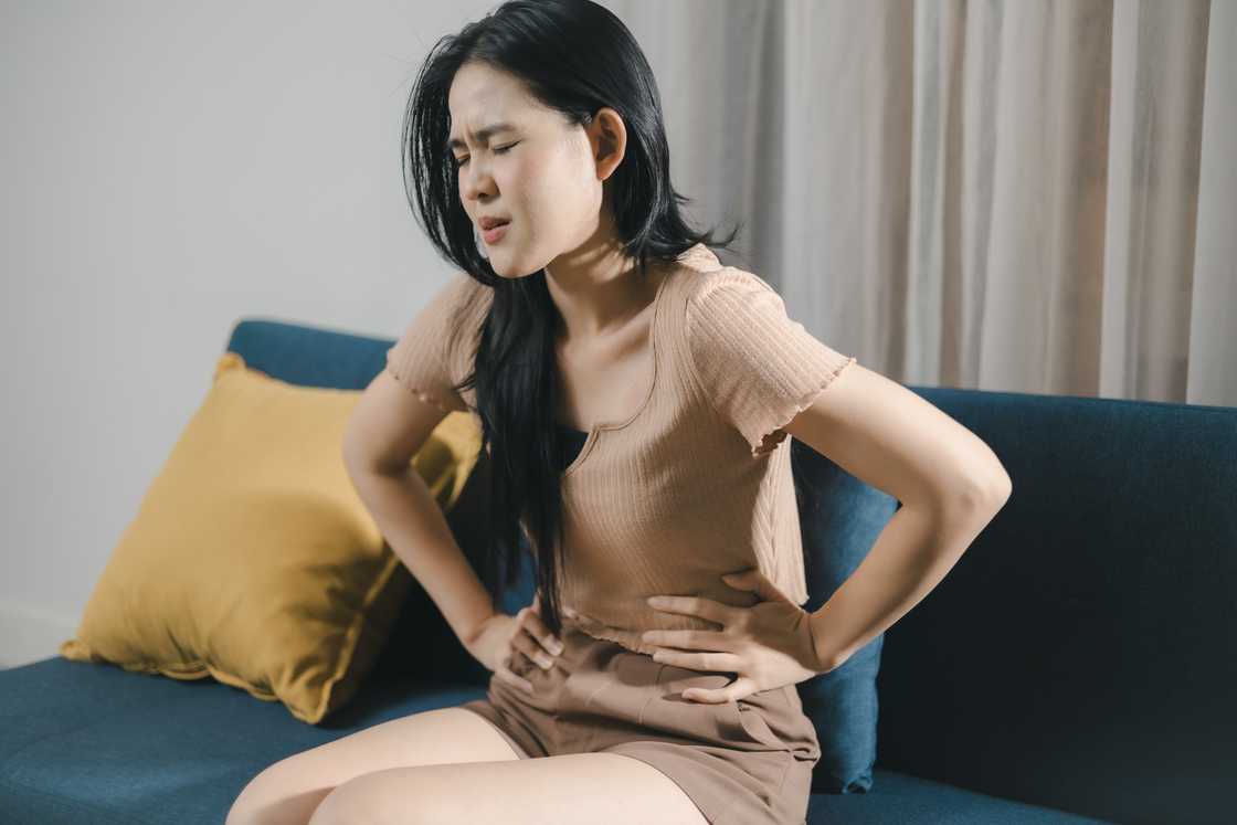 A woman who feels unwell is sitting on the sofa