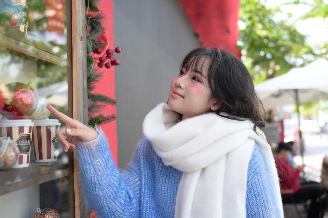 A young woman enjoys holiday decor outdoors.