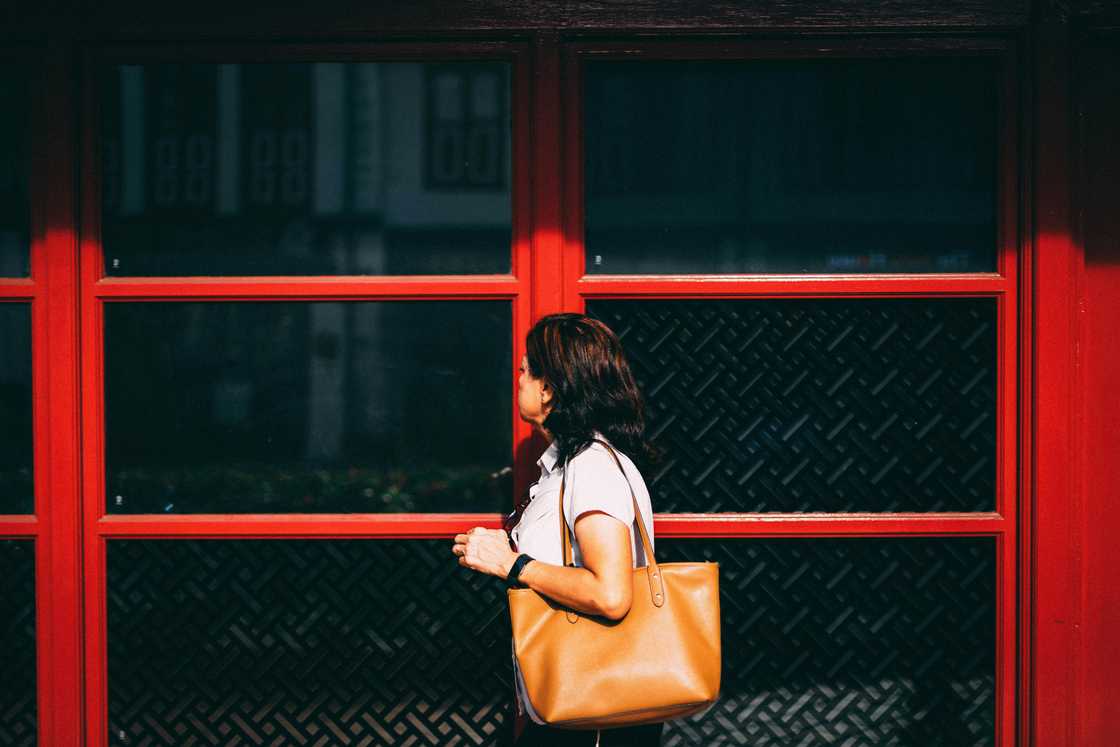 A lady standing near a red school gate A lady standing near a red school gate
