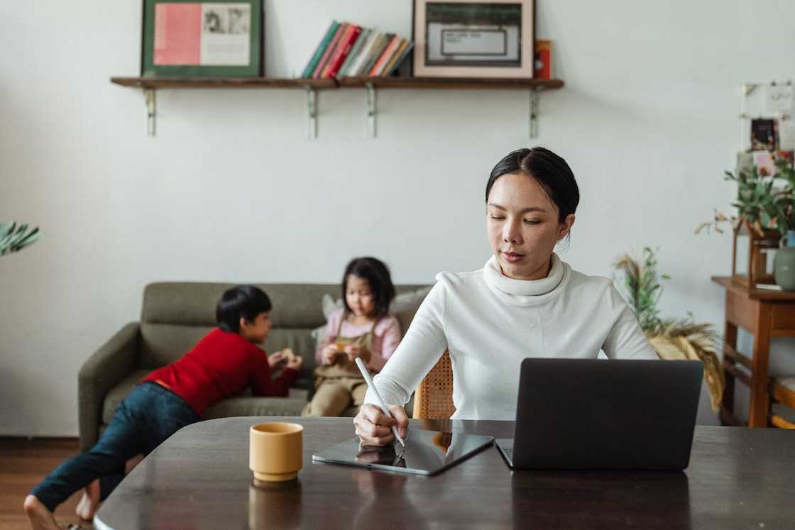 A woman works at a table with a tablet and a laptop. A woman works at a table with a tablet and a laptop.