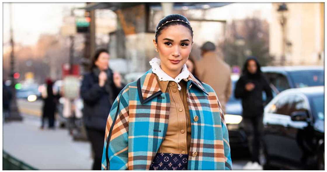 Heart Evangelista, wearing a tan leather long shirt, Louis Vuitton mini skirt, blue and beige checked coat, beige boots and printed bag, during Paris Fashion Week Heart Evangelista, wearing a tan leather long shirt, Louis Vuitton mini skirt, blue and beige checked coat, beige boots and printed bag, during Paris Fashion Week