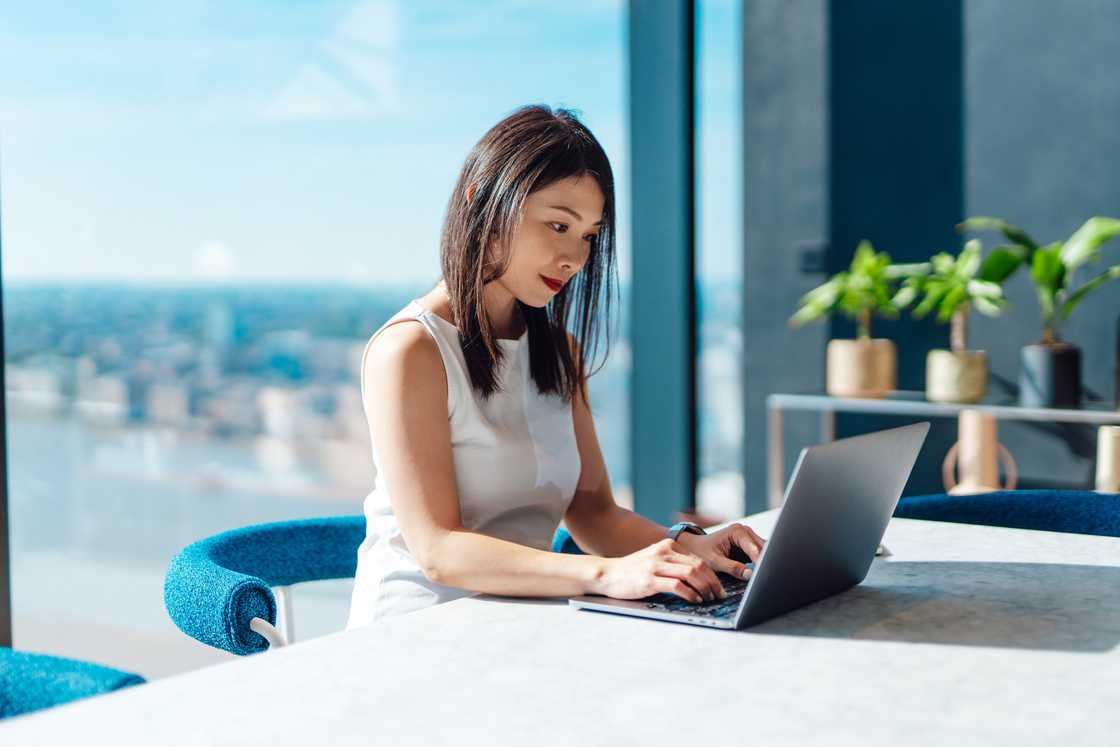 A woman working with laptop while sitting by the window