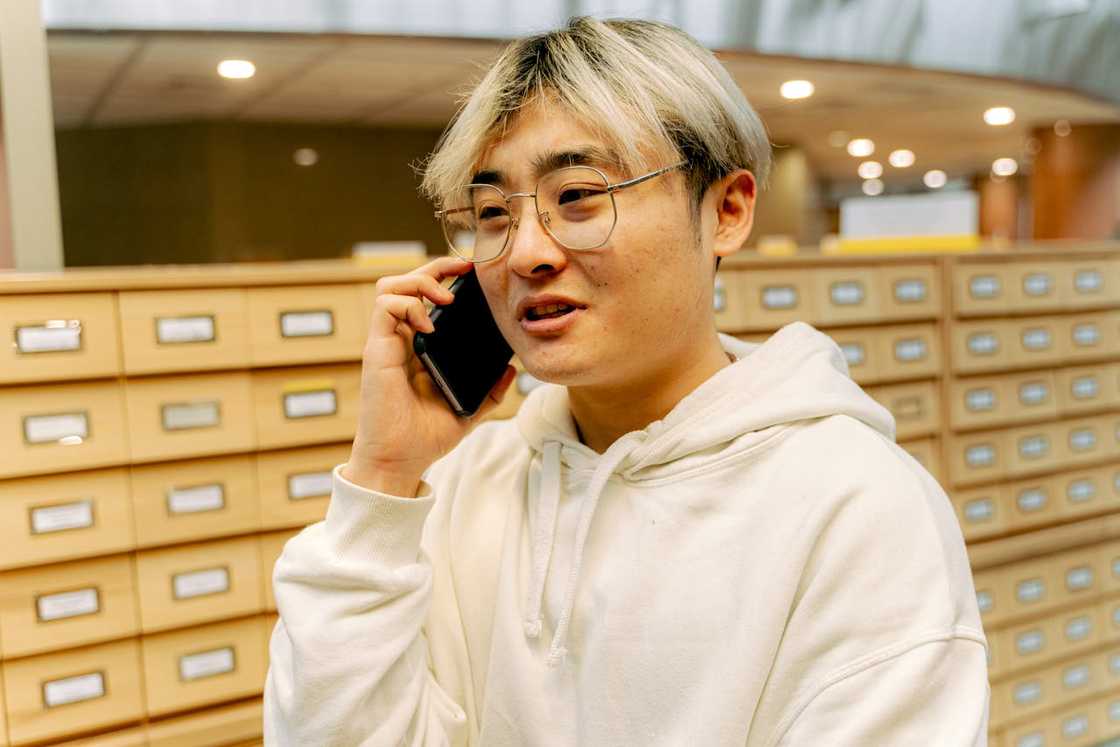 A person in a hoodie talks on the phone. A person in a hoodie talks on the phone.