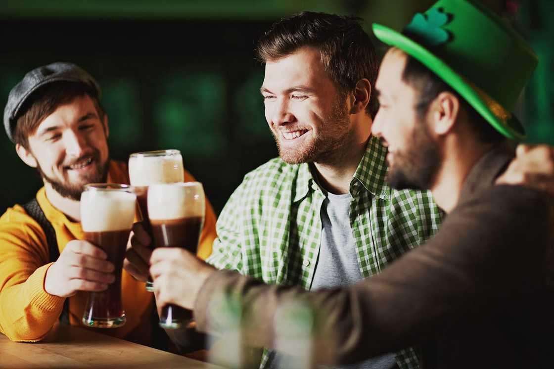 Friends cheer, smile, and drink beer during an outing.