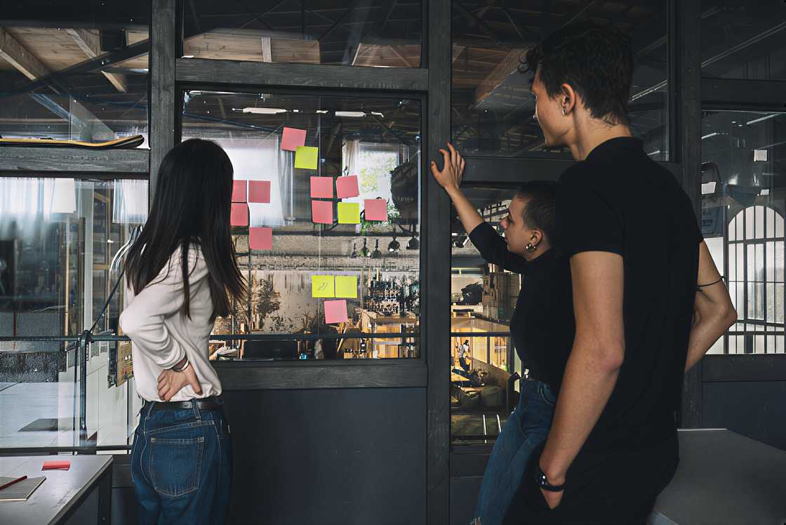 Male and female coworkers are reading sticky notes