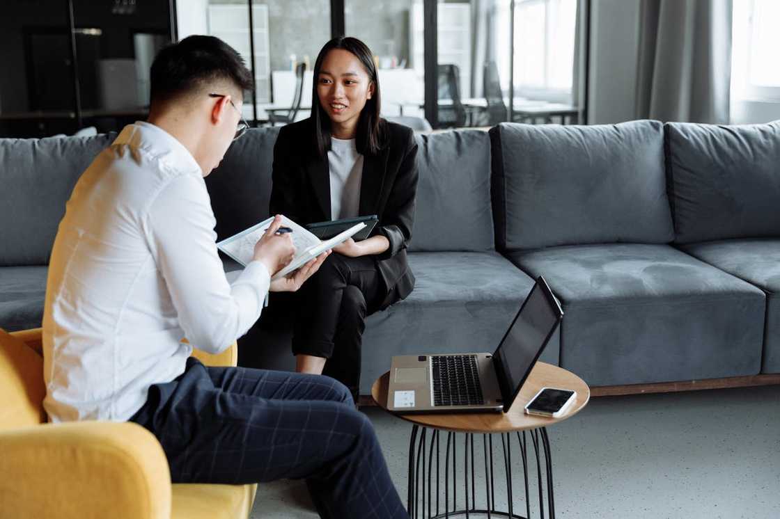 A pair of coworkers reviews paperwork during a meeting in a modern office lounge. A pair of coworkers reviews paperwork during a meeting in a modern office lounge.