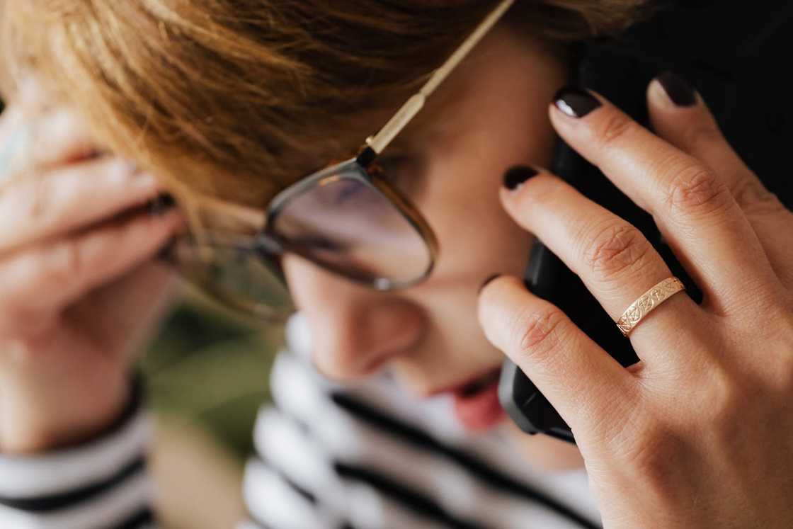 Close-up of a woman wearing glasses while speaking on a phone.