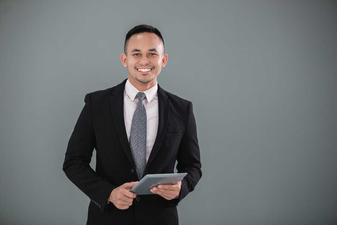 A cheerful young businessman holding his tablet and smile