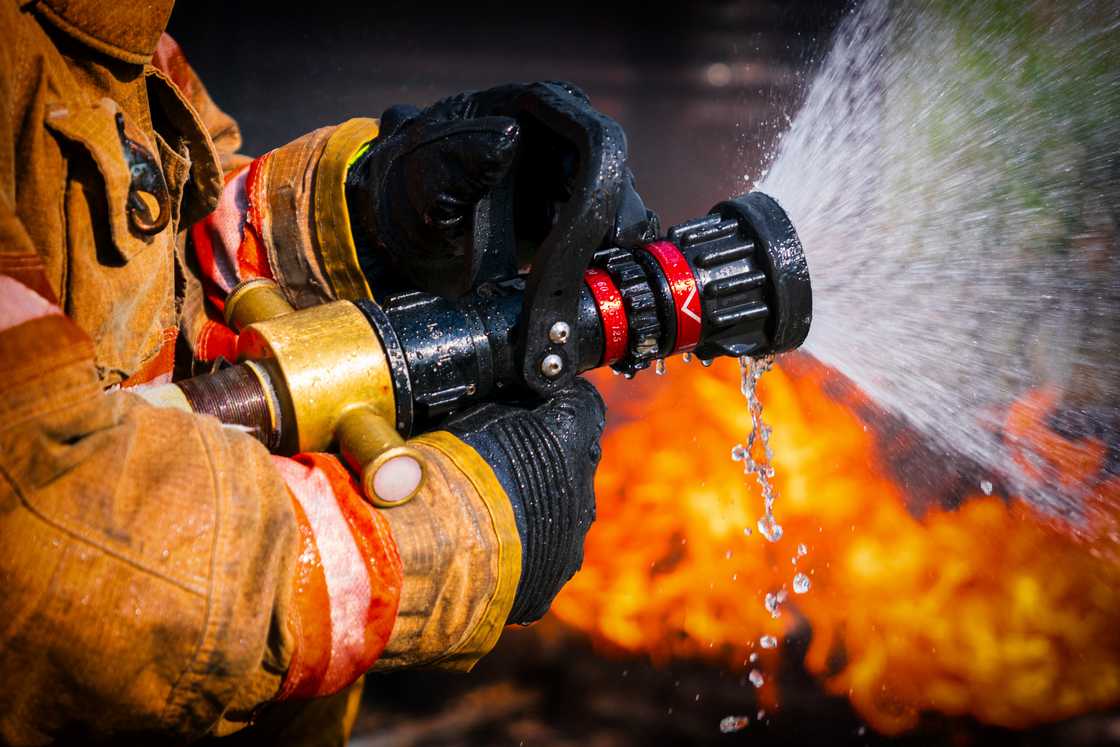 A firefighter using water to extinguish fire A firefighter using water to extinguish fire