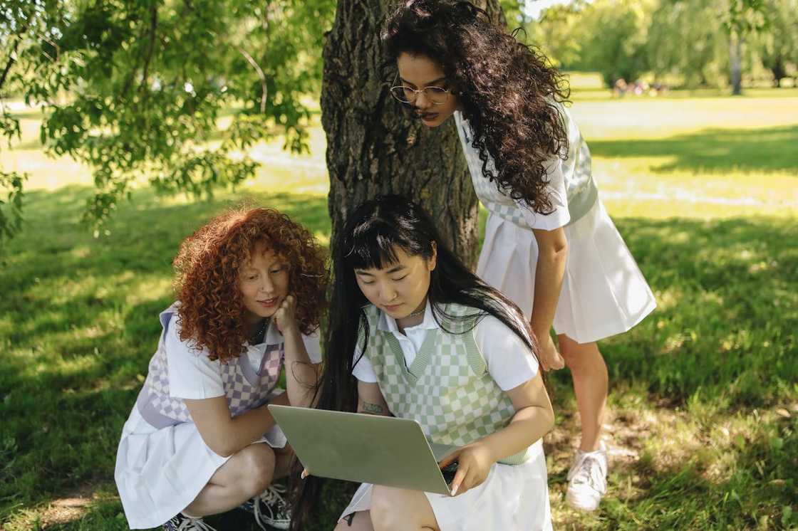 Girls studying happily under a tree after school.