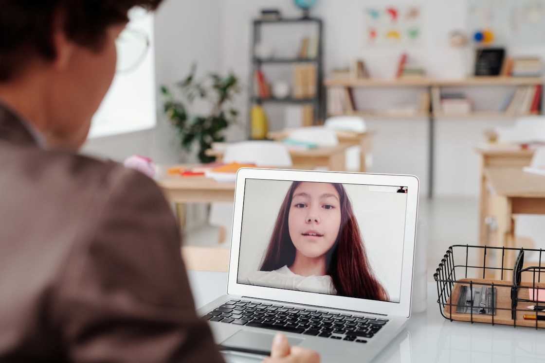 A laptop shows a video call in a classroom. A laptop shows a video call in a classroom.