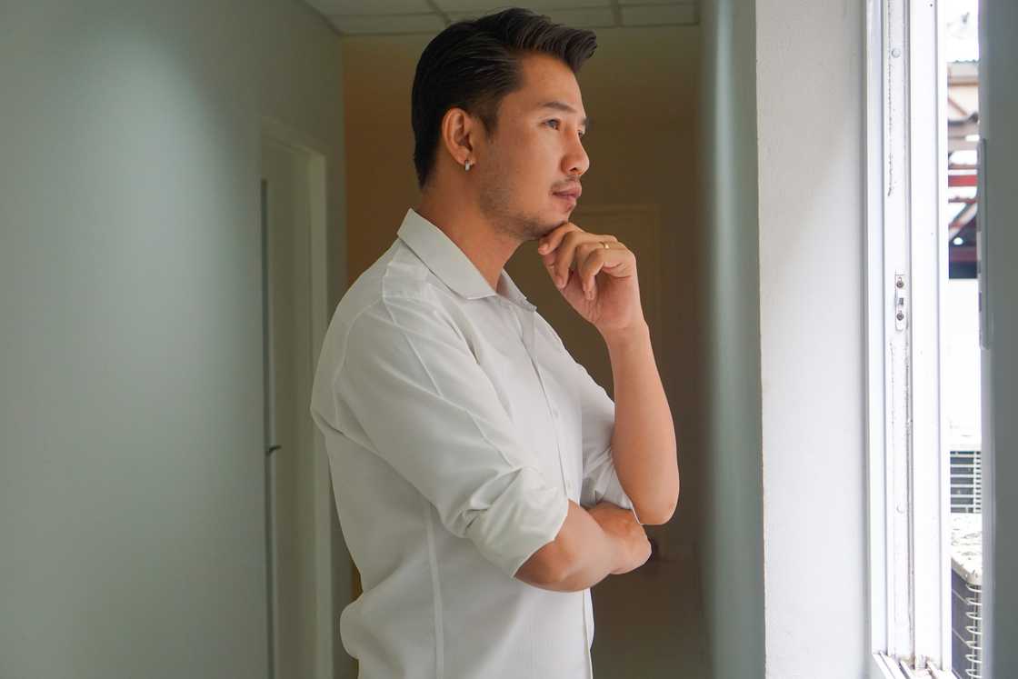 A man wearing a white shirt thinking while looking outside A man wearing a white shirt thinking while looking outside